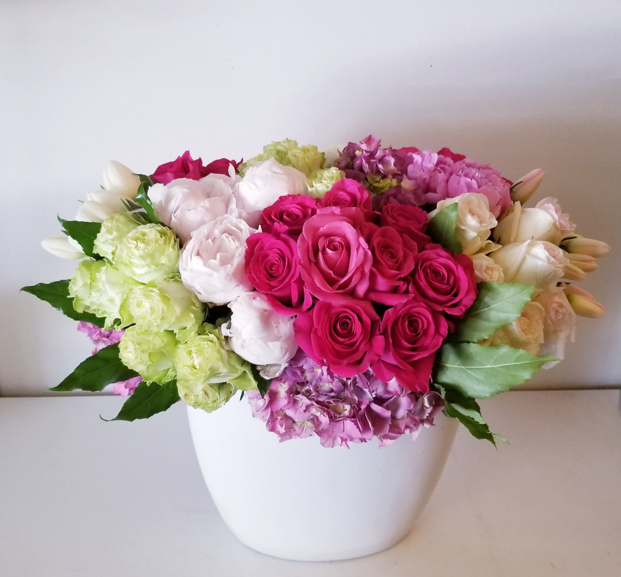 Bella - White Oval shape ceramic vase arrangement composed of beautiful high end blooms in white, bright and light pinks and green.