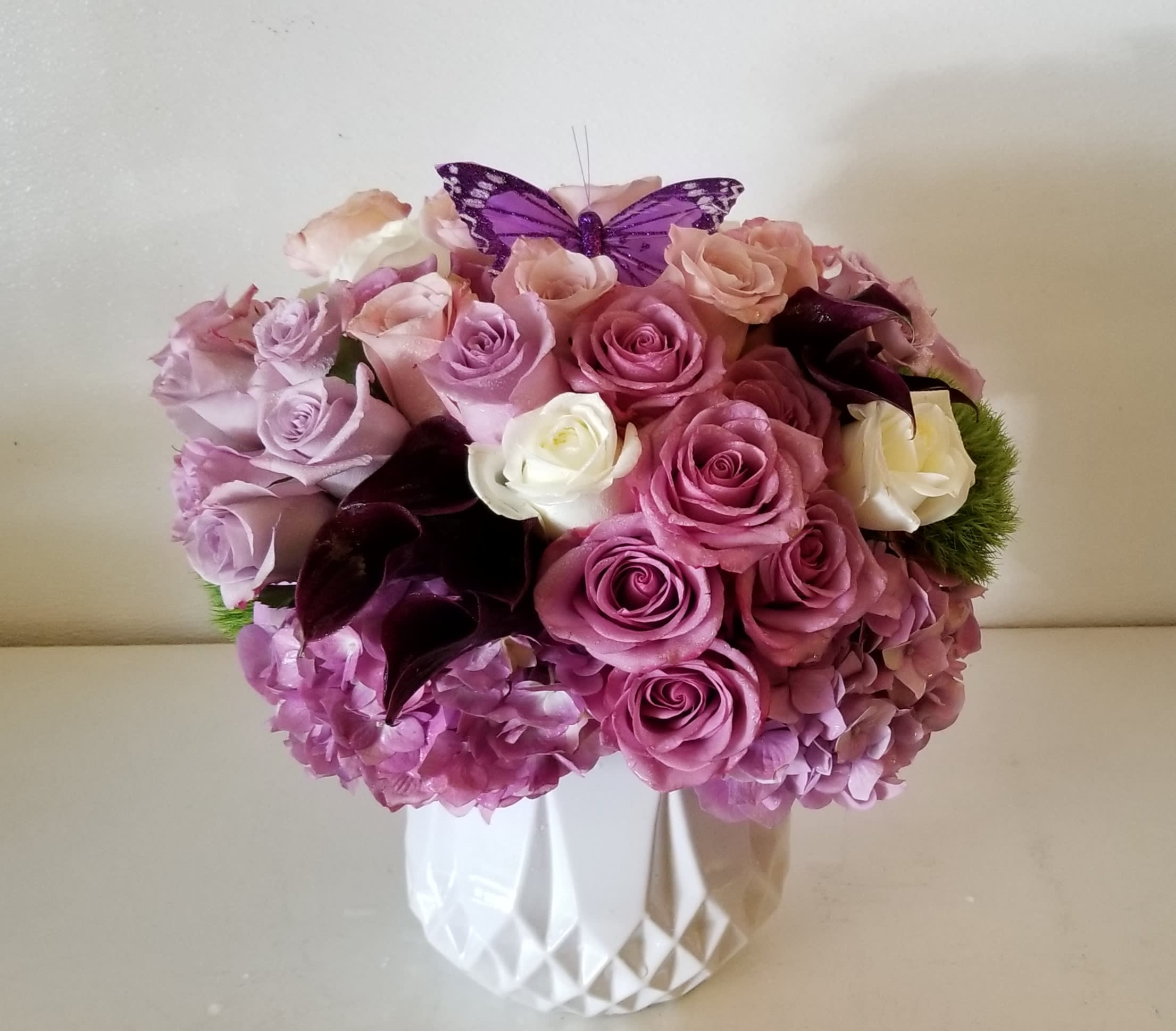 Dusty Pink - Low and lush arrangement in white ceramic vessel, composed of different shades of dusty pink  and light lavender roses, hydrangeas and plum mini calla lilies.