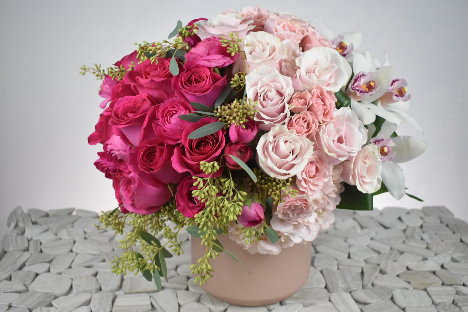 WOW Pink Ombre - This Wonderful floral design is created an ombre style. its made in a pink ceramic vase and It starts on the left with some Hot Pink roses, Hot pink ranunculus it then goes to a soft pink color with light pink hydrangeas, light pink roses, and light pink spray roses, it ends with the  white side on your right with some white cymbidiums, perfectly match with some folded aspidistra and siriu greens.  Perfect for  birthday flowers anniversary flower  just because flowers  congratulations flowers  Get well flowers  Christmas flowers Valentines Day flowers Mother's Day flowers