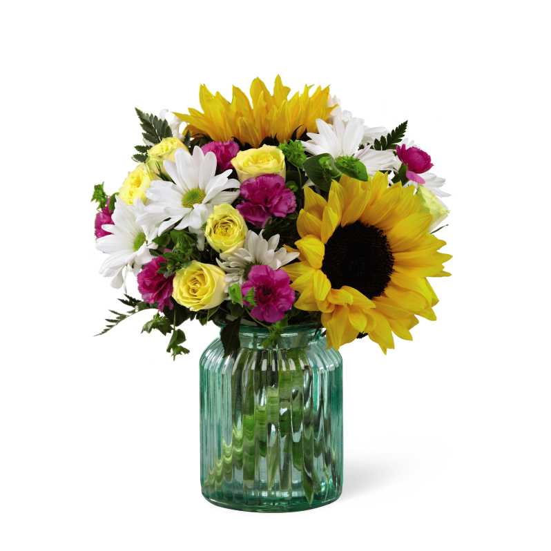 Better Homes and Gardens Sunlit Meadow Bouquet - FTD proudly presents the Better Homes and Gardens Sunlit Meadow Bouquet. This simply lovely bouquet makes a terrific way to add color and country charm to any Mother's Day celebration. Its casual cheer and brilliant color palette comes from the combination of brilliant sunflowers, yellow spray roses, magenta mini carnations, white traditional daisies and lush green accents in an aqua blue canister glass vase. Its fresh from the gardenÂ look is perfect for celebrating special birthdays and other milestone events, or to express your thanksÂ or get wellÂ wishes.
