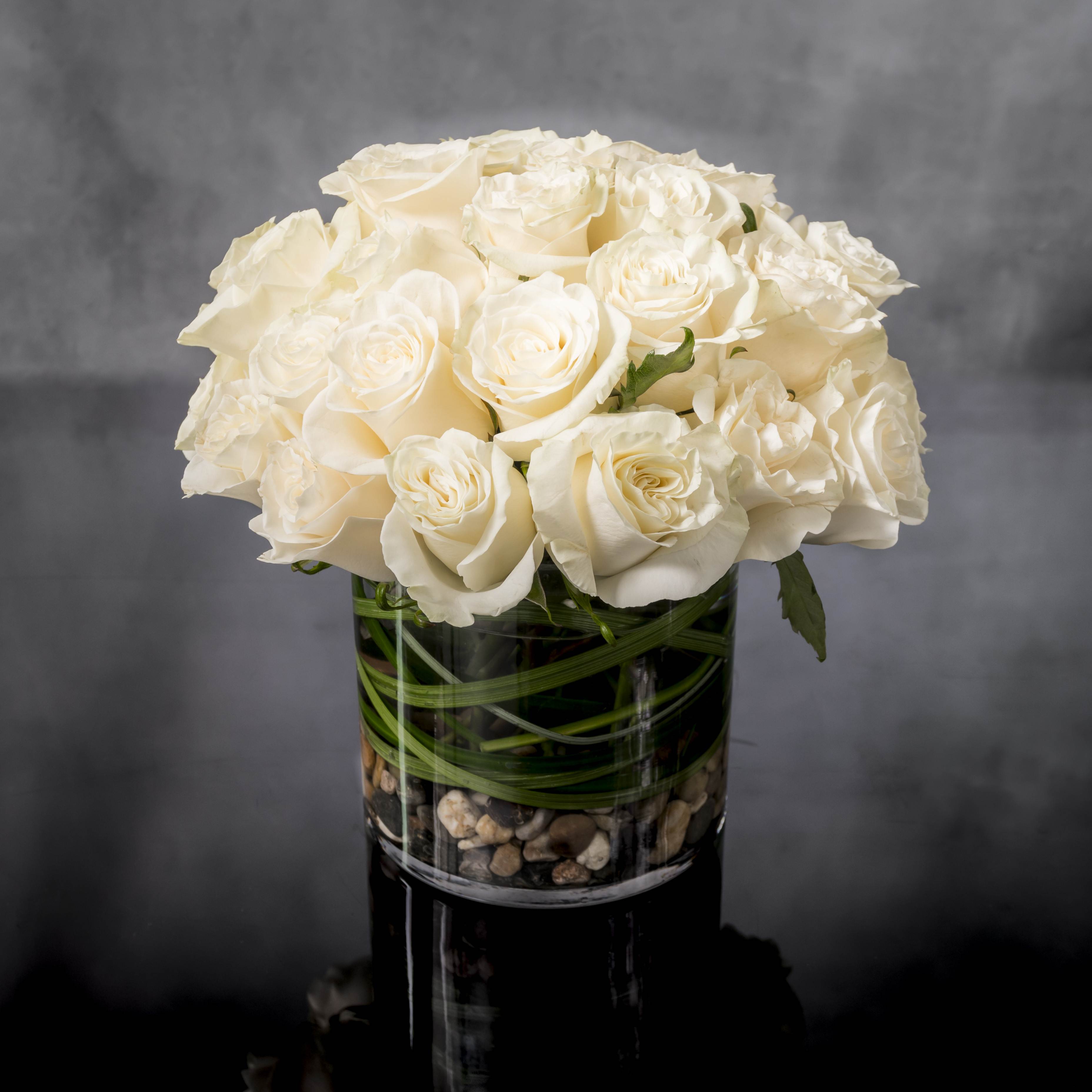Wonderful in White - Simplicity, purity, and elegance are expressed in this design. Specialty premium white Ecuadorian roses are clustered in a fresh, full and delicate arrangement.  Standard: 2 Dozen Roses as pictured 6 inch Cylinder  Approx. 8&quot; round