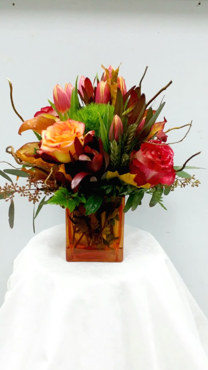 Autumnal Fest - Festive autumn arrangement - Roses, tulips, safari plant, solidago in a amber vase. Tulips are not usually in season at this time of year. Order ahead of time, we can deliver in this beautiful arrangement!