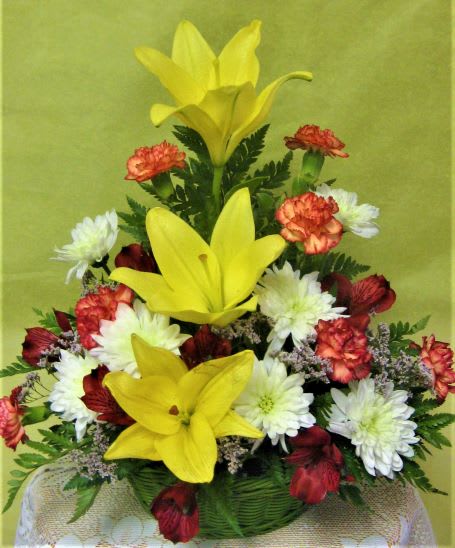 Sunrise surprise - This arrangement shows colors of a morning sunrise.  Yellow lilies, orange mini carnations alstroemeria and white chrysanthemums are arranged in a basket. Adding an occasion mylar balloon makes these flowers appropriate for any occasion. 