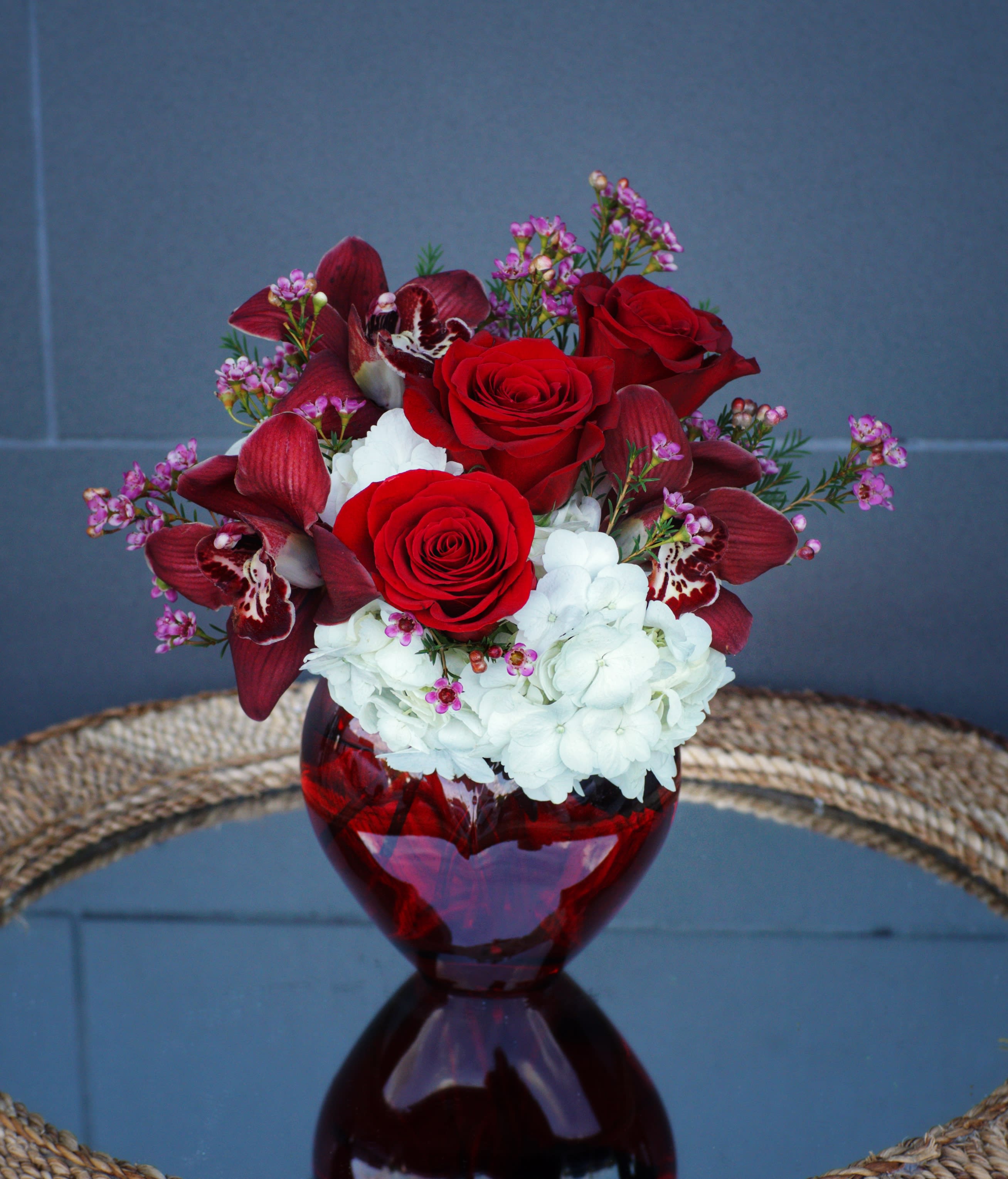 Ruby - Like a charming ruby, this design includes orchids, roses and nice accents in a red vase.