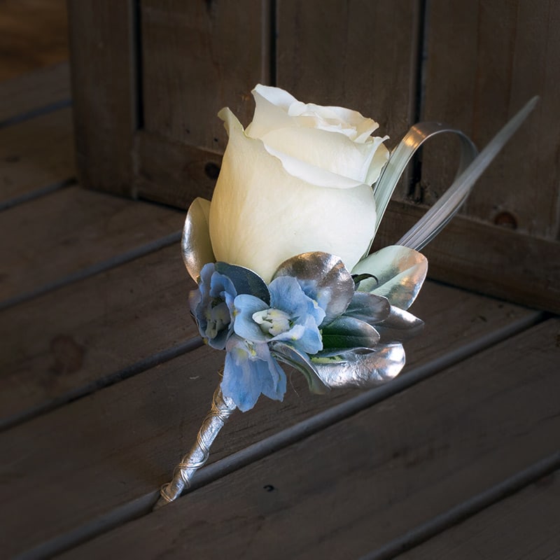 White Rose with Delphinium Boutineer - A single white rose with delphinium blue and silver accents.