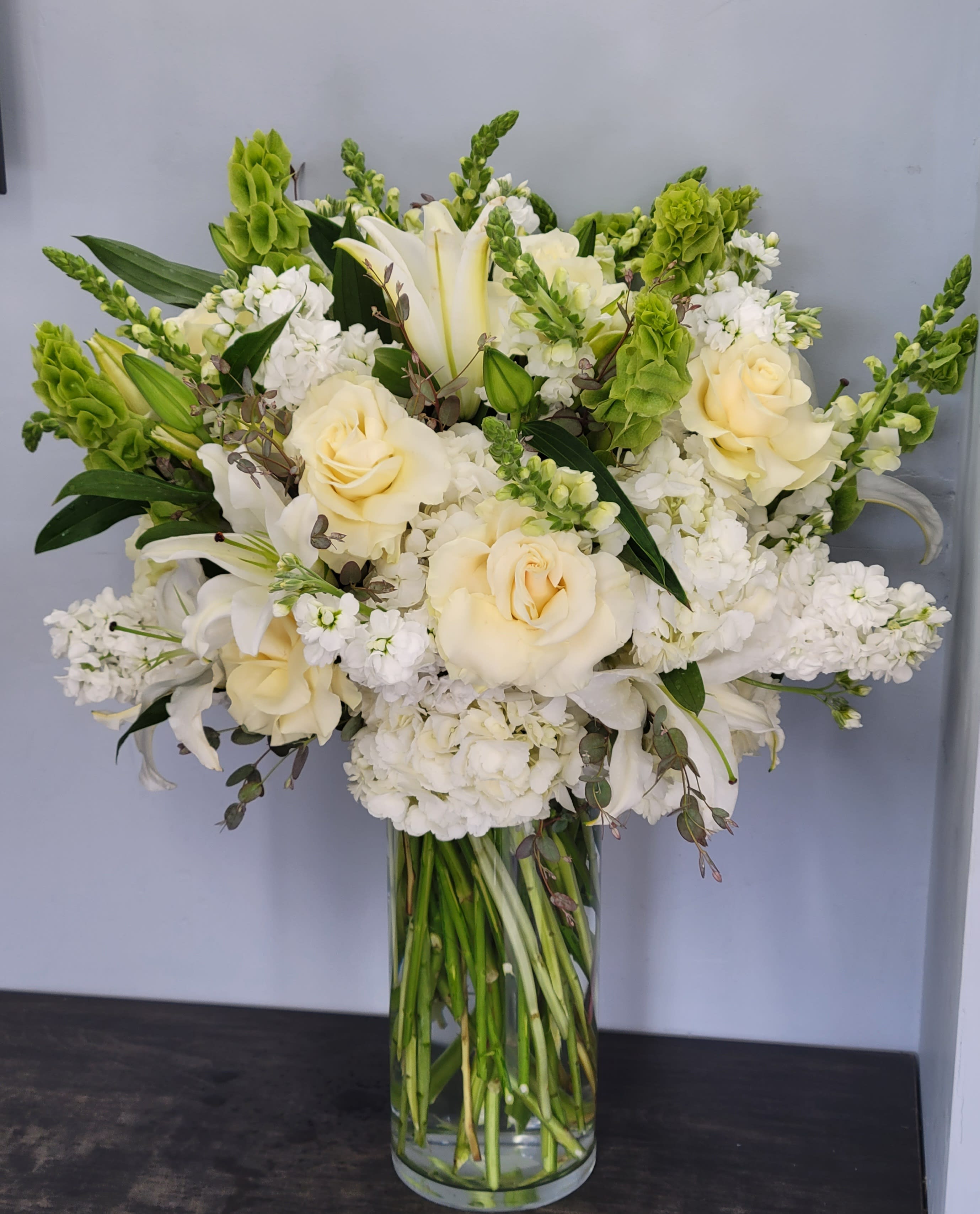 Country French Arrangement - Country French arrangement with lilies, hydrangea, roses, bells of Ireland, and snap dragons. Dimensions 14-18 in diameter, 16-22 in height.