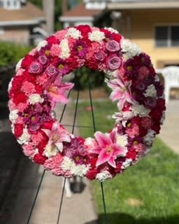 Pink and Purple Tribute Wreath  - A round wreath filled with pink and purple mixed flowers