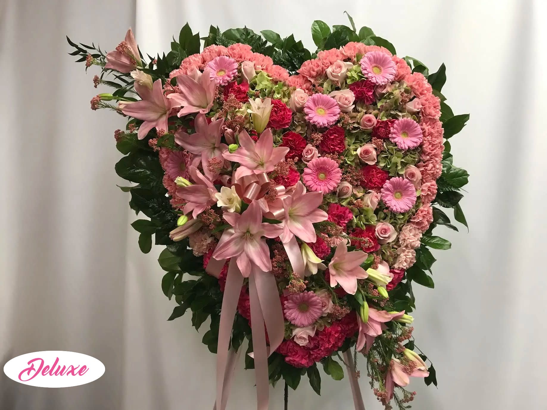 Pretty in Pink Standing Heart Pretty in Pink Standing Heart - This Solid Heart is lovely in all shades of pink. Flowers include Lilies, Roses, Gerber Daisys a Carnation boarder and a green Hydrangea backing.