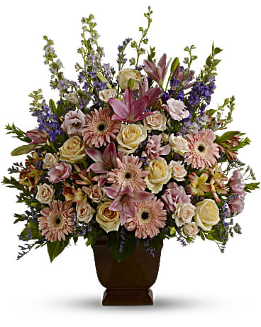Loving Grace Tribute - Honor a beautiful person with a beautiful bouquet. This lush, luxurious arrangement of assorted funeral flowers communicates your sympathy in soothing shades of soft pink, peach and lavender.   •This dramatic display of blooms features flowers such as peach roses, light pink spray roses, pink asiatic lilies, pink gerberas, pink alstroemeria, pink lisianthus, lavender and purple larkspur, purple limonium and greens including myrtle and salal. •Delivered in an exclusive Noble Heritage urn. •Orientation: One-Sided 