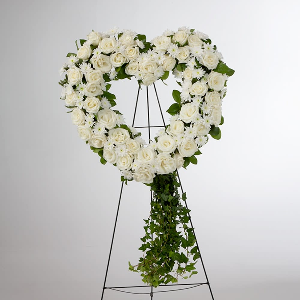 Love in our Hearts by BloomNation™  - An all white tribute, this open heart shaped design shows your everlasting love. Featuring a variety of white flowers and greenery, this heart with a trail of ivy compliments the beauty of life. Other color options and accents available.  May we add a banner for your loved one? Please call for options and sizes. Mini version available for inside casket starting at 75.00