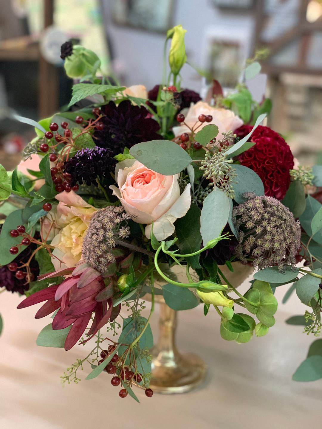 Heirloom Elegance Heirloom Elegance - A golden pedestal arrives with garden roses, protea, pincushion flower, berries, lisianthus, eucalyptus just in time for the party.