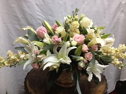 Pretty in Pastel - * White oriental lilies * Creme stock * Pastel pink roses * White roses * Pink and white spray roses * White mini calla lilies * Assorted greenery * Professionally arranged in a brown round basket This lovely arrangement can be customized in the color of your choosing. Make this change with the season's colors for individualized taste.