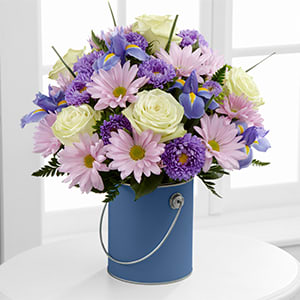 Blue Tranquility Bouquet Blue Tranquility Bouquet - This Bouquet speaks to peaceful moments in nature's beauty, blooming with cool hues to calm and relax the mind. Exquisite jade green roses form a pop of light amongst blue iris, lavender traditional daisies, lavender matsumoto asters and lush greens to form a simply gorgeous flower bouquet. Presented in a periwinkle quart-size decorative paint can inspired vase, this flower arrangement is wonderful gift to send as a get well offering, to express your thanks, or even to convey your deepest sympathies.