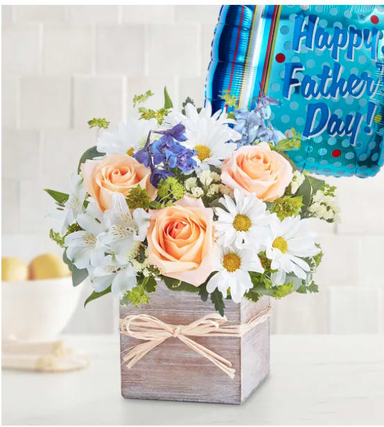 Ocean Breeze for Dad Ocean Breeze for Dad - Give Dad the day of relaxation he deserves with our Coastal Breeze arrangement. Inspired by the soothing shades of a seaside retreat, it’s artistically designed in our grey-washed wooden cube, featuring natural tones and textures, and finished with raffia. Paired with a festive balloon, this gift sends your sentiments in cool, summery style. One-sided arrangement with peach roses, blue delphinium, white Peruvian lilies (alstroemeria) and daisy poms, yellow statice; accented with assorted greenery. Father’s Day Mylar balloon, measures 18"D; design may vary due to local availability”. Our florists hand-design each arrangement, so colors and varieties may vary due to local availability.