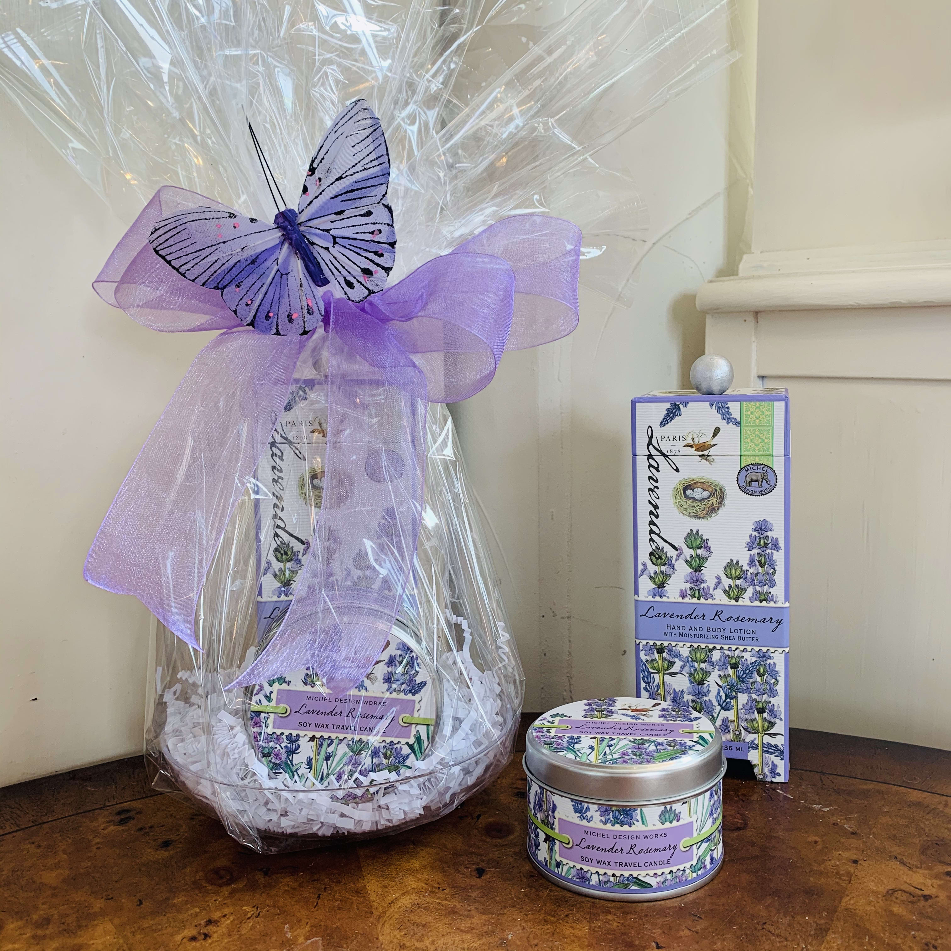 Lavender Rosemary Petite Gift Basket - This petite gift basket includes one hand and body lotion and one scented travel candle beautifully wrapped up and ready to go with a large bow and sweet butterfly accent.    Items included: 1) Our hand and body lotion is made with shea butter, aloe, and other botanical ingredients. The decorative bottle of luxurious lotion is packaged in a beautiful keepsake gift box.  8 fl. oz. / 236 ml lotion.  2) Our all-natural, 100% soy wax travel candle is nontoxic, biodegradable and clean burning. The handy, decorative, and versatile tin can be used at home or when traveling, indoors or out.  4 oz./113.4 g. Over 20 hrs. approximate burn time.  Fragrance: The unmistakable scent of lavender with rosemary and a hint of eucalyptus.  Customizable gift baskets available upon request. Please give us a call at 775-348-6161 for assistance putting together the perfect aromatherapy basket for your loved one. 