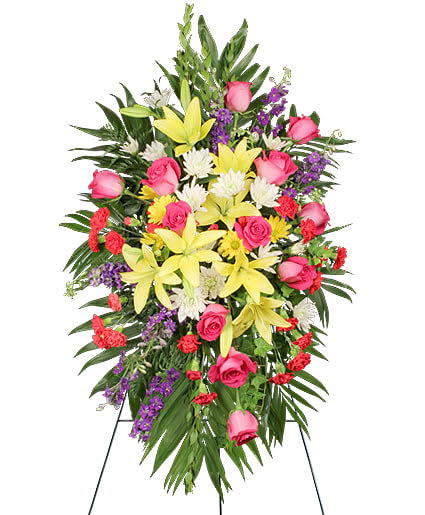 Fondest Farewell Fondest Farewell - Honor your loved ones with this bright standing spray, made of hot pink roses, yellow lilies, purple larkspur, red mini carnations, white cushion poms, and yellow daisy poms.