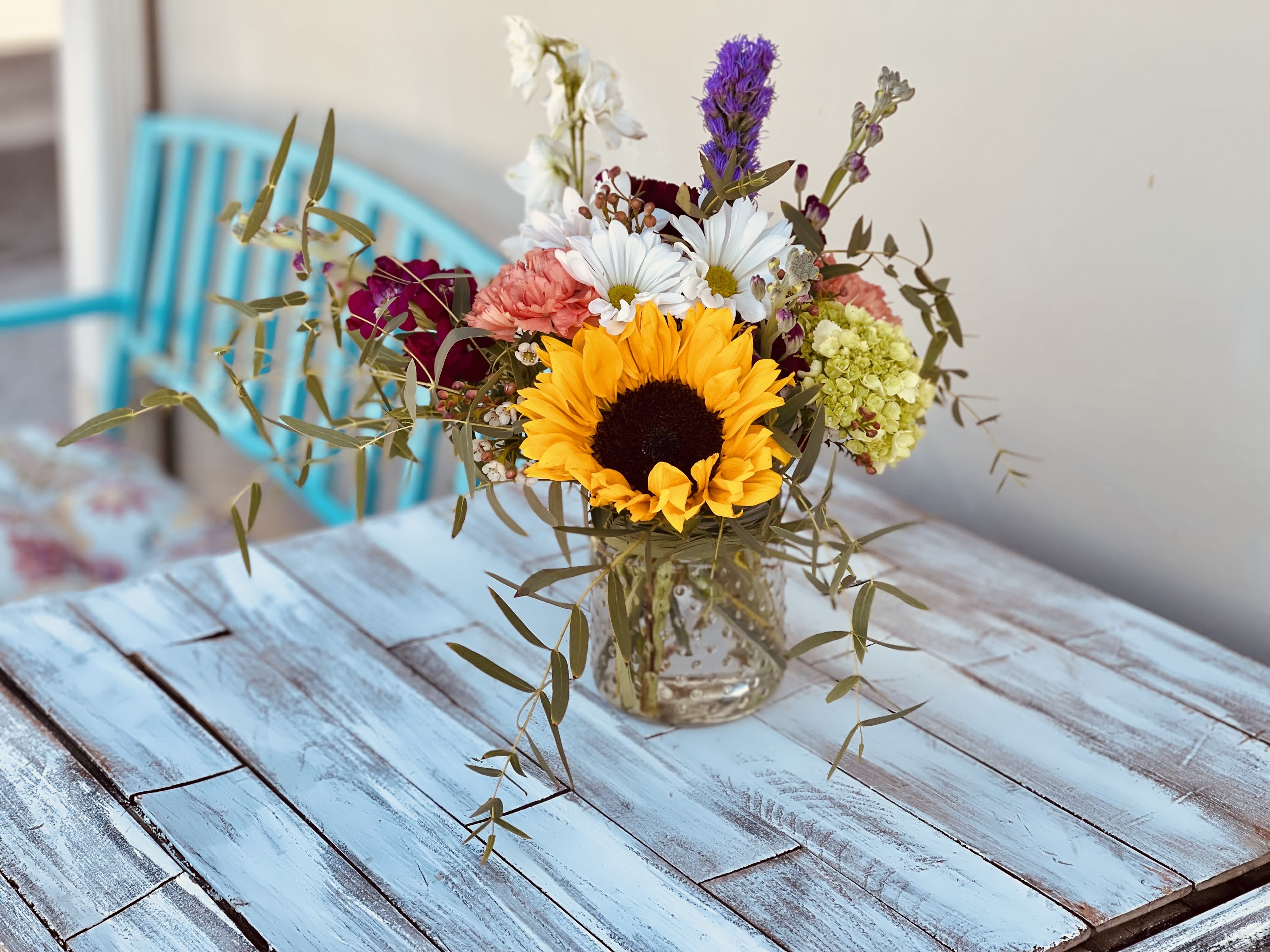 Sunny Sunflower Sunny Sunflower - Sunbright Sunflower will brighten anyone's day, Gunnie Eucalyptus, purple stock, hint of hydrangea, splash of daisy and top off with purple liatris. In a bubbled glass jar.