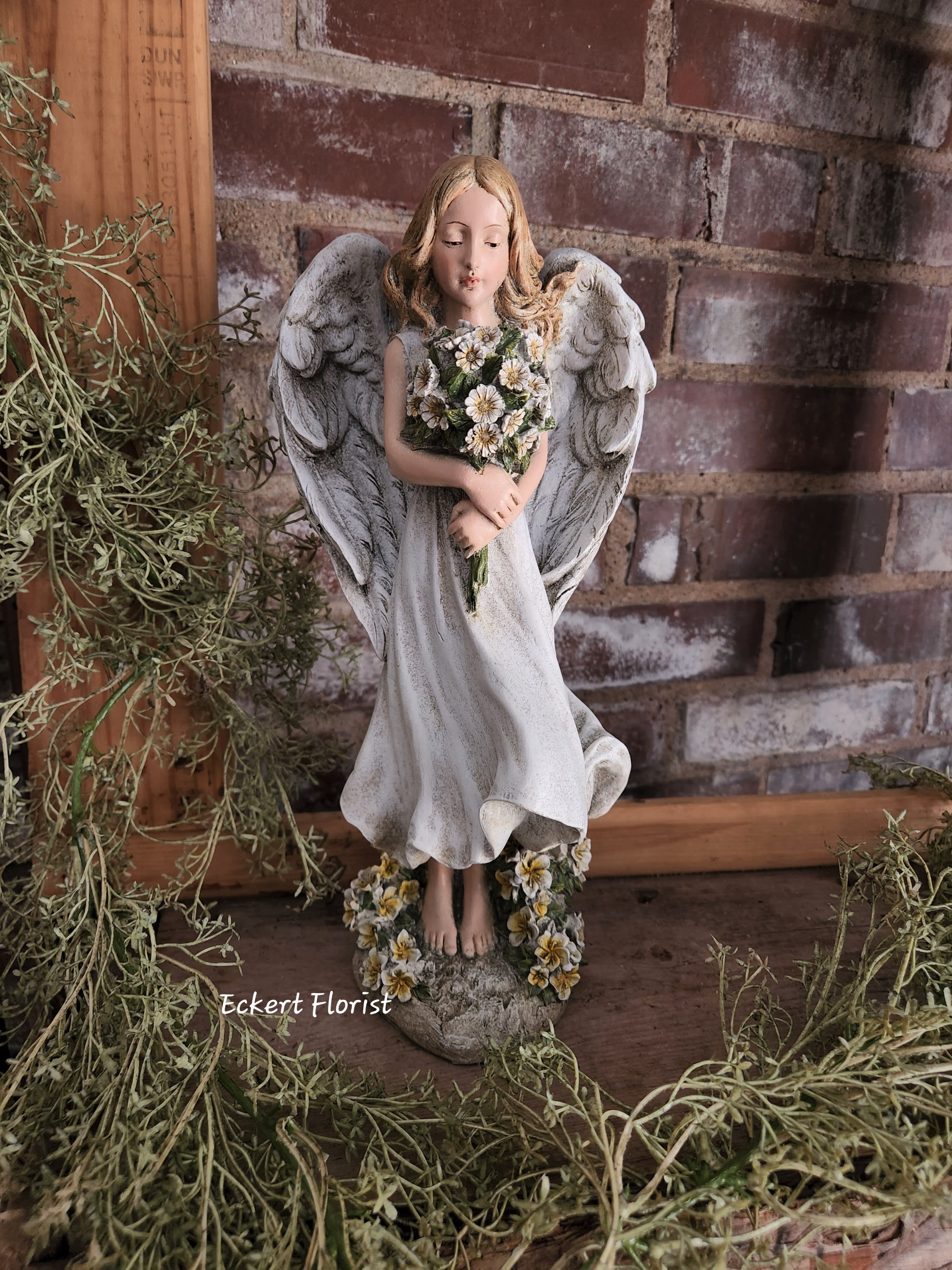 Eckert Florist's Angel With Flowers Eckert Florist's Angel With Flowers - Resin angel measures Approx. 12.5" H X 5.5" W May be added to a fresh arrangement or green plant. See Deluxe or Premium upgrades. *OUR LOCAL DELIVERY ONLY