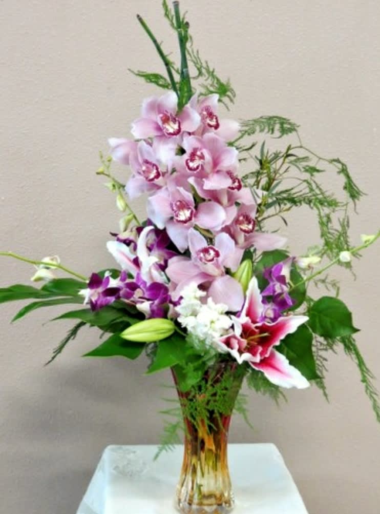 Tropical Beauty - This is a beautiful tropical arrangement designed using cymbidium orchids, dendrobium orchids, stargazer lilies, stock, and filler greens. Dimensions: 27&quot;x12&quot;