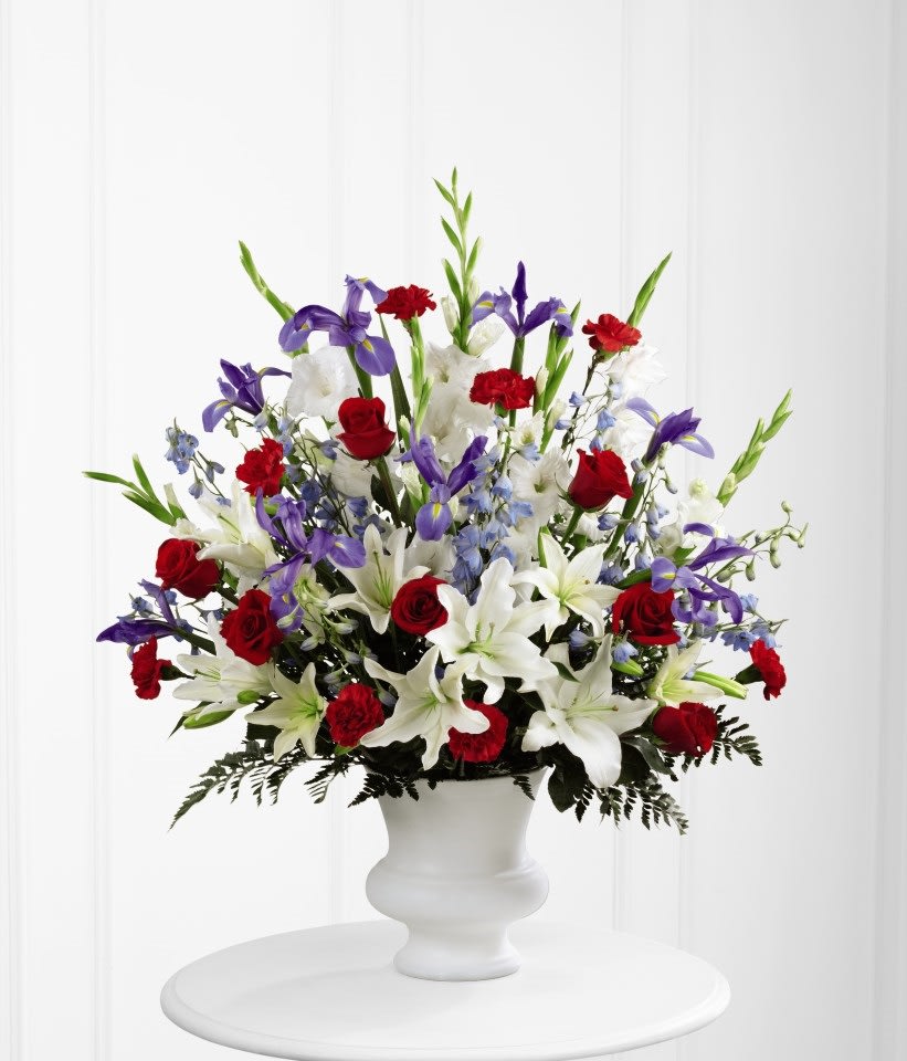 SAFF The Cherished Farewell Arrangement - The Cherished Farewell Arrangement is an elegant display of patriotic beauty to honor your loved one at their final farewell service. Red roses, red carnations, white gladiolus, light blue delphinium, blue iris, white Oriental lilies, white Asiatic lilies and lush greens are elegantly arranged in a white plastic urn to create a stunning way to say your last goodbye. GOOD arrangement includes 28 stems. Approximately 32&quot;H x 26&quot;W  Your purchase includes a complimentary personalized gift message.