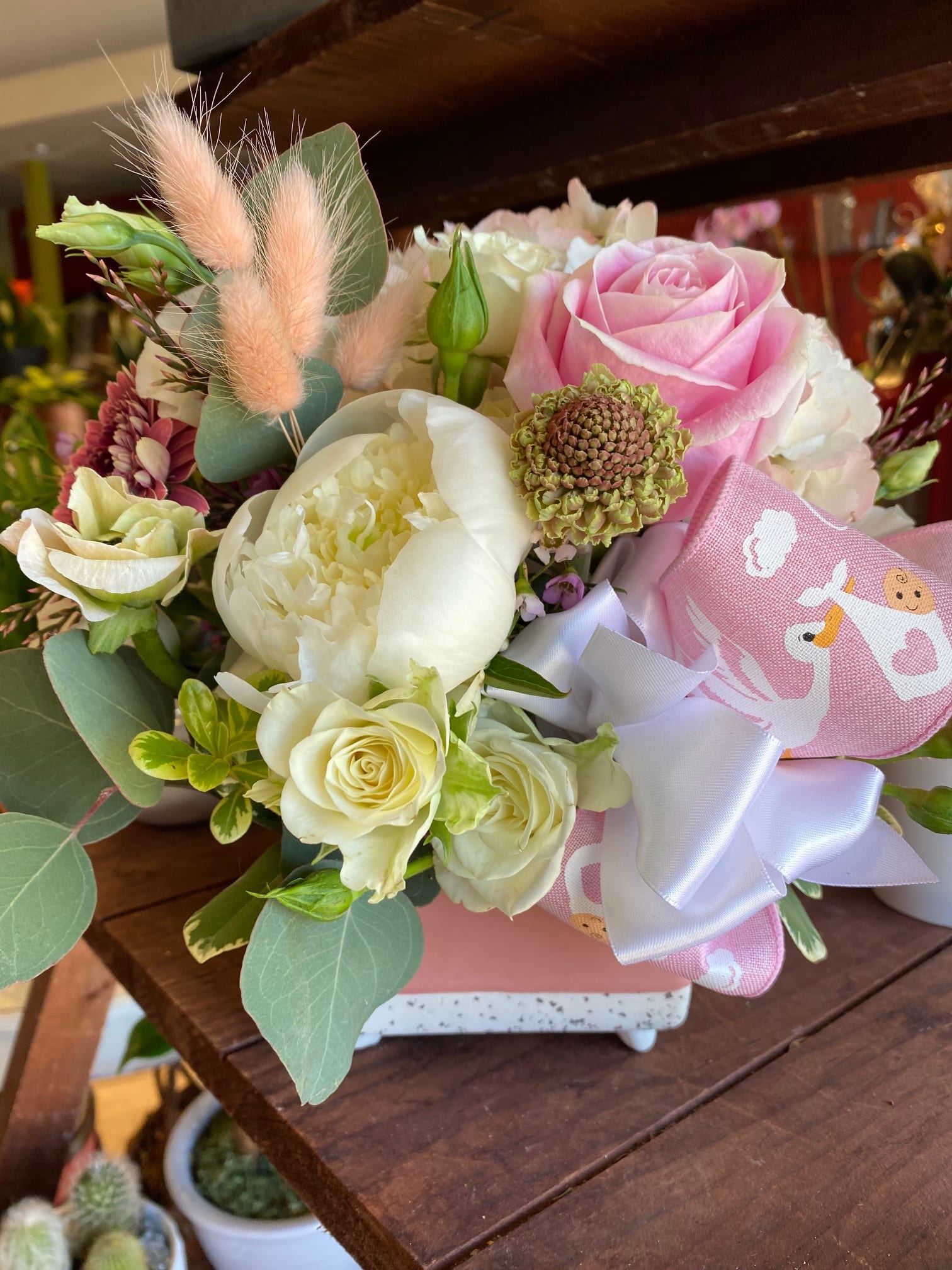 Bunny Tails and Baby Girls Bunny Tails and Baby Girls - This charming custom baby girl arrangement is sweet and unique. We've chosen a contemporary square pink pot and filled it with a special collection of flowers. The 'bunny tails' are the fuzzy pink poofs....affectionately known as bunny tails in the preserved flower world! Be different, and send this one!!