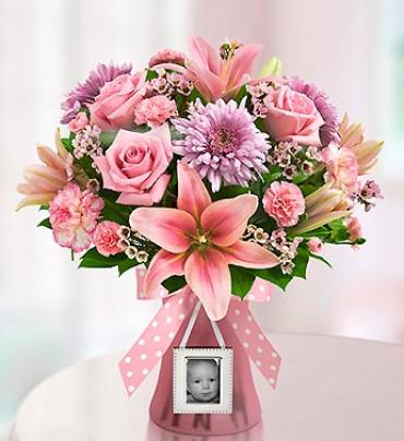 Sweet Baby Girl Arrangement -  Send sweet and elegant congratulations for the birth of their baby girl with our gorgeous arrangement of fresh roses, lilies, carnations and more. Hand-arranged in a stylish pink frosted glass vase, featuring a mini magnetic photo frame and tied with an adorable pink polka dot bow. (Vase/Basket style may vary)    Item # 91362 