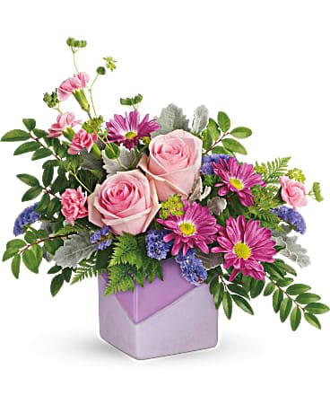 Teleflora's Love Squared Bouquet - Your love for mom multiplies every day. Celebrate her with this contemporary cube featuring a fun, two-toned matte-glossy finish and radiant rose bouquet! This lush bouquet includes pink roses, pink miniature carnations, purple daisy spray chrysanthemums, purple sinuata statice, bupleurum, leatherleaf fern, huckleberry, and dusty miller. Delivered in a Love Squared cube.