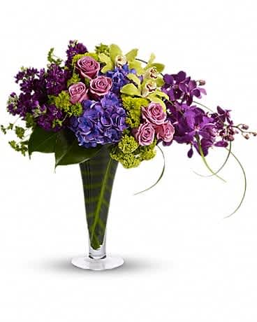 Your Majesty - This stunning tropical bouquet really is fit for a queen. It's an elegant mix of vibrant flowers set in a tall vase lined with tropical leaves. It makes a beautiful addition to a modern home or outstanding office dÃ©cor. A lovely mix of blue hydrangea, green cymbidium orchids, mokara orchids, lavender roses and lots more are delivered in a footed and flared glass vase. Make magic happen for her majesty!