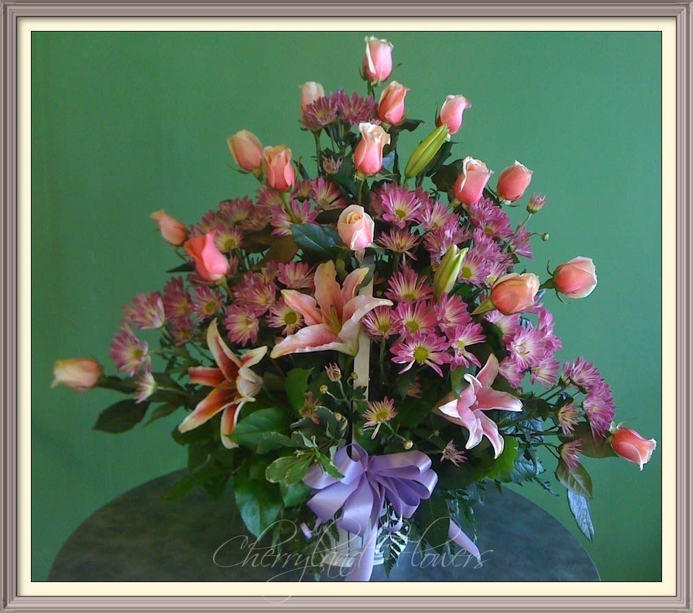 Rosa - This Luxurious Rose &amp; Lily Basket features a fresh assortment of two dozen pink roses, lavender daisies, pink stargazer lilies, and leather leaves artfully arranged in a basket adorned with a bow.  CF123