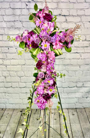 The Shrouded Cross - Honor your loved one with a floral cross that truly represents their devotion to their friends, family, and community. The Shrouded Cross standing spray brings radiant beauty and cherished comfort to those who are mourning. Featuring vibrant bi-colored roses in stunning hues of lavender, pink, and maroon with an aspidistra accent and a luscious sea of ivy, this floral cross is a peaceful and reassuring addition to any funeral service, memorial service, or wake.
