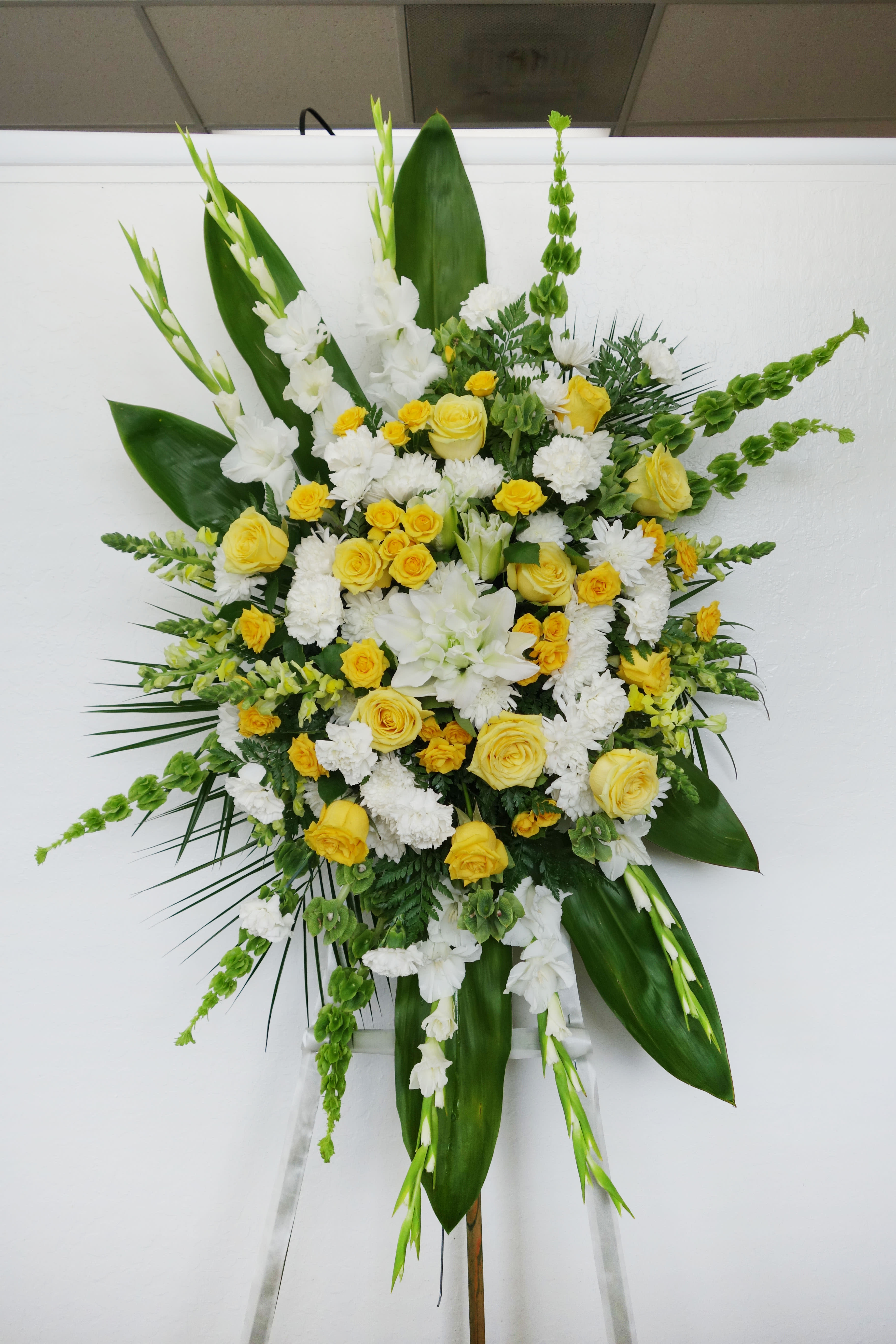 SS#24 Brilliant Light Standing Spray - May their soul shine brightly upon our lives forever just as the sun gives us warmth and illuminates the sky. This yellow and white standing spray features roses, carnations, spray roses, mini carnations, stocks, gladiolus, and mixed foliage.   The arrangement is approximately 48&quot; H and 24&quot; W.