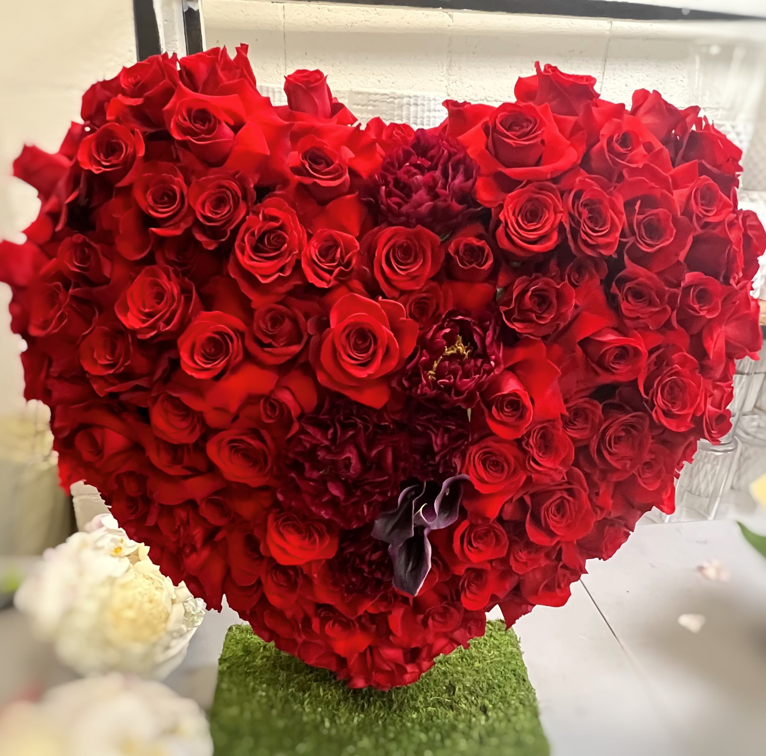 Heart red passion  - A heart shaped arrangement approximately 20 by 35-inches with red reflex roses and a touch of red peonies and burgundy calla Lilies. Very eye-catching! Just the gift for that special loved one when you need to show them how much you care. Make there day by getting them this big arrangement.