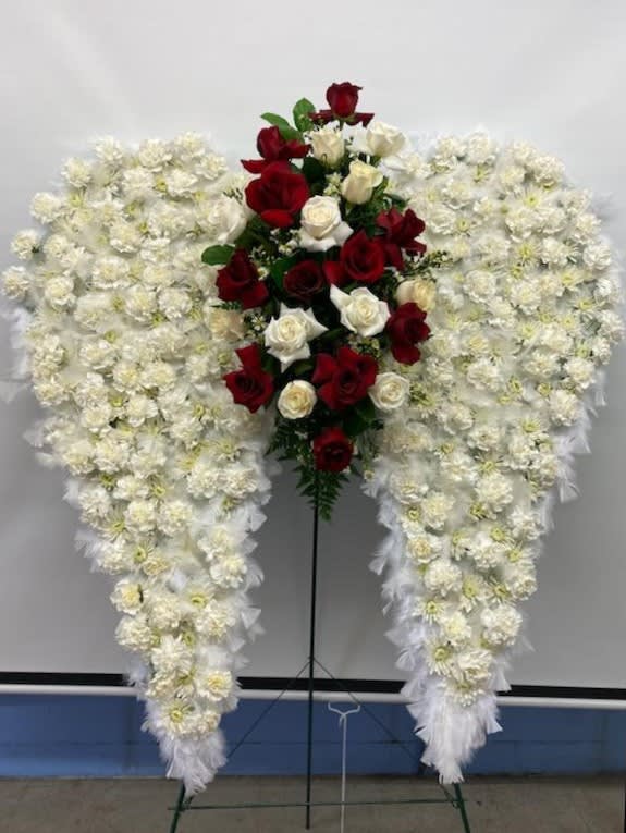 My eternal Angel - Angelic and majestic these unique wings are the perfect way to send your loved one off in style with a Wing and a Prayer. Stands approximately 6ft.  with carnations mums and feathers along outside edge. The color of the center ROSES can be changed. Call 713 944 7673additional info.