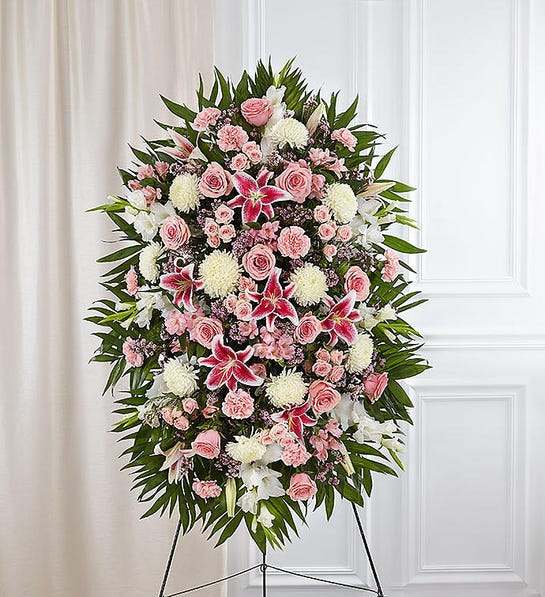 Deepest Sympathies Standing Spray-Pink &amp; White - This Sympathy Standing Spray, in shades of peach, orange and white, is a beautiful symbol of your sympathy and support. Pink roses, stargazer lilies, spray roses, white carnations and more An appropriate gift for family, friends and business associates to send directly to the funeral home Our florists use only the freshest flowers available so colors and varieties may vary.