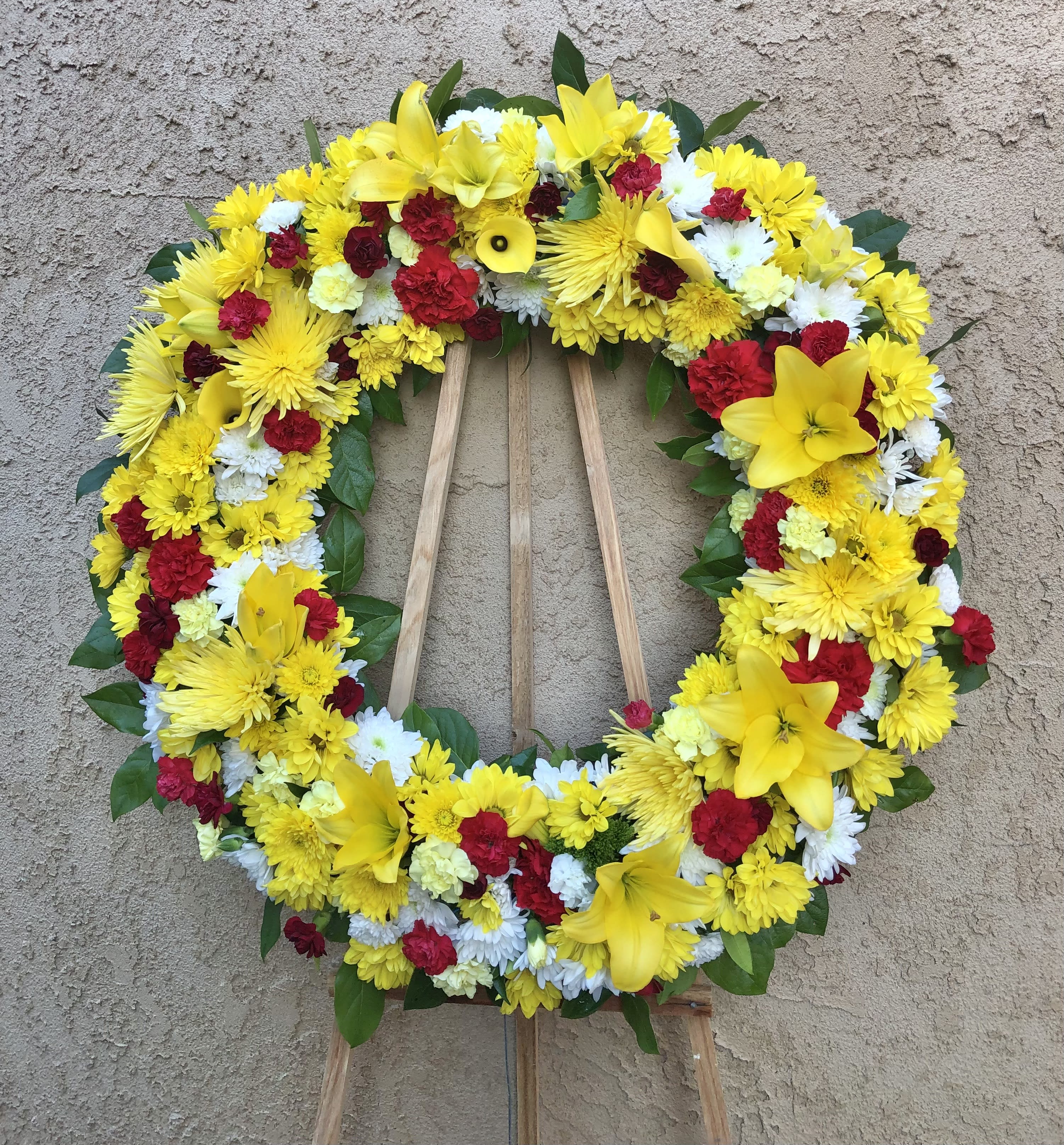 Fruitful and Golden - Radiating standing spray funeral arrangement with mixed yellow and red flowers with green accents. Featuring yellow lilies, calla lilies, daisies, carnations, and mums. 