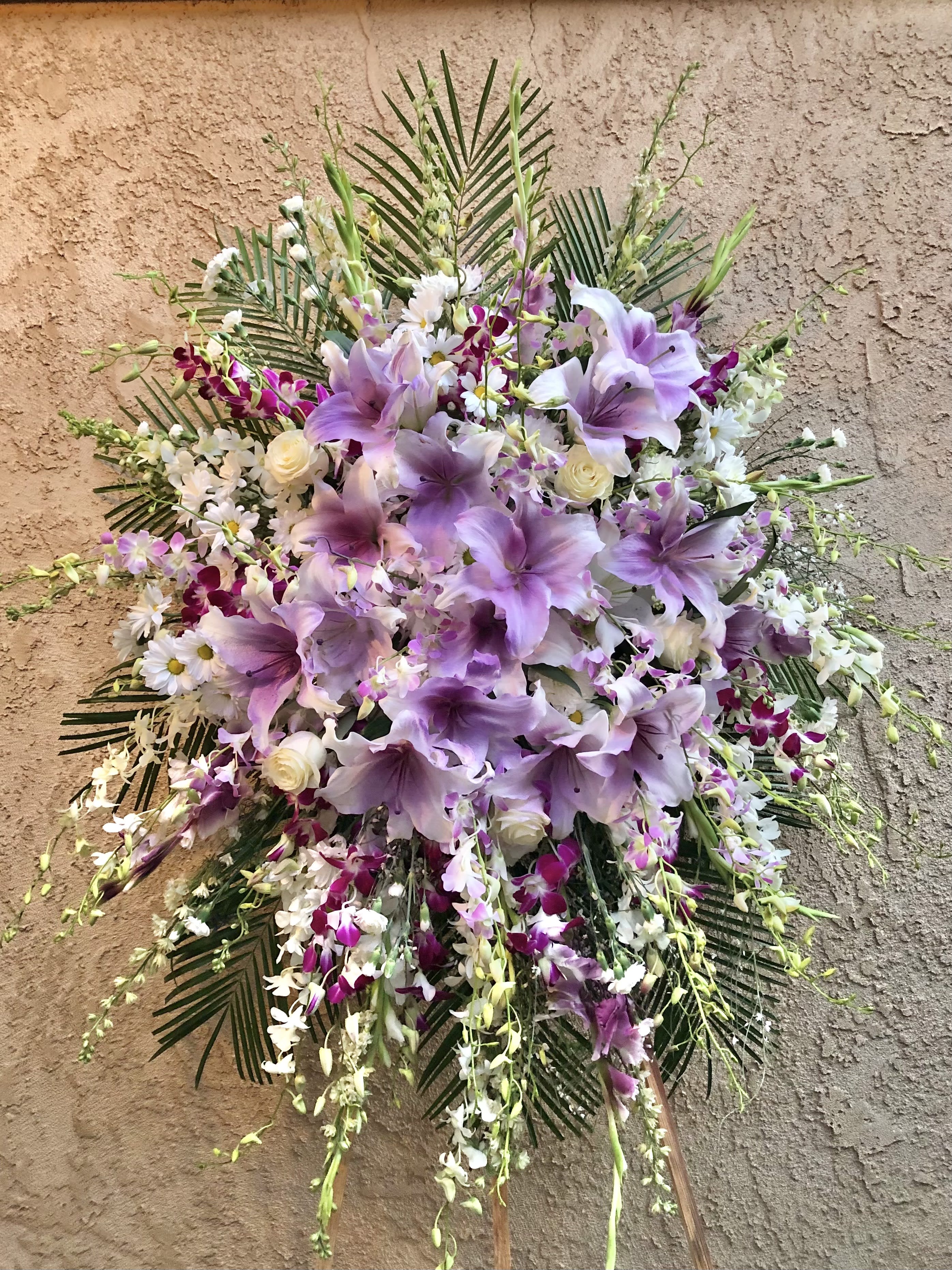 Midsummer Breeze - Beautiful standing funeral spray arrangement with purple and white mixed flowers. Featuring purple lilies, orchids, white roses, daises, and gladius.