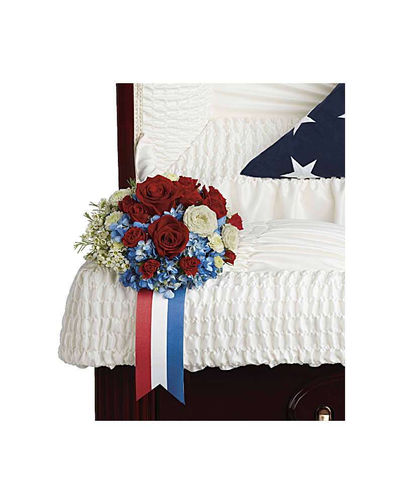 Loving Legacy Casket Insert - Celebrate the honorable legacy of your loved one with this patriotic display of blue hydrangea and white and red roses. Blue hydrangea, red roses, red spray roses, white spray roses, white button spray chrysanthemums, and white waxflower are accented with galax leaf.