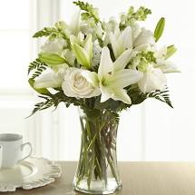The FTD® Eternal Friendship™ Bouquet - An exuberance of bright and beautiful white blossoms provides an exquisite way to deliver your expressions of sympathy and comfort. This life affirming tribute combines white roses, snapdragons and Asiatic lilies accented by lush greens arranged in a clear glass gathering vase. An excellent choice for a wake, funeral service or for sending your condolences to the home of grieving family or friends.  Your purchase includes a complimentary personalized gift message.