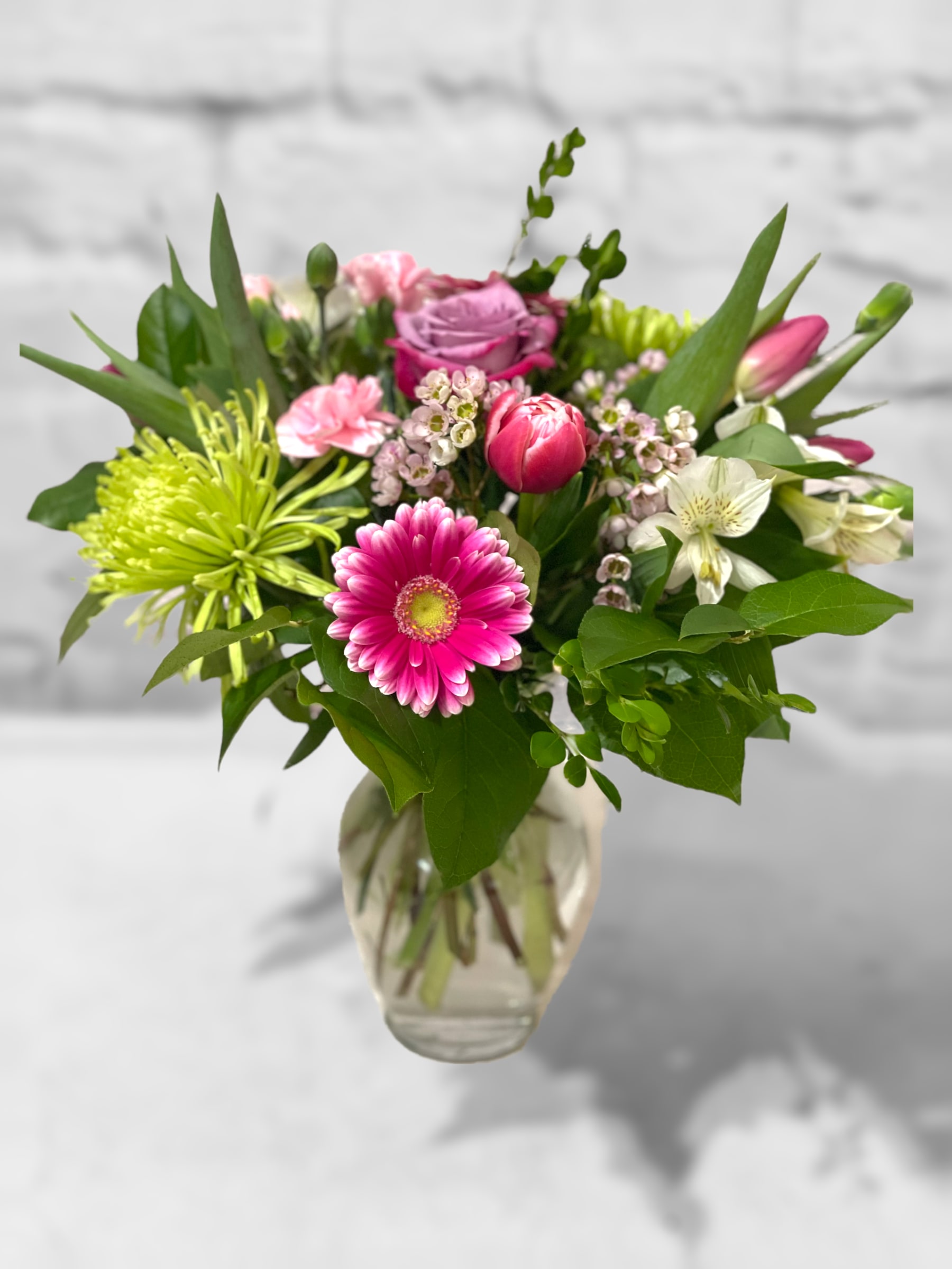 Summer Cheer - A lovely mix of seasonal blooms artfully arranged in a glass vase. Sure the brighten the day!