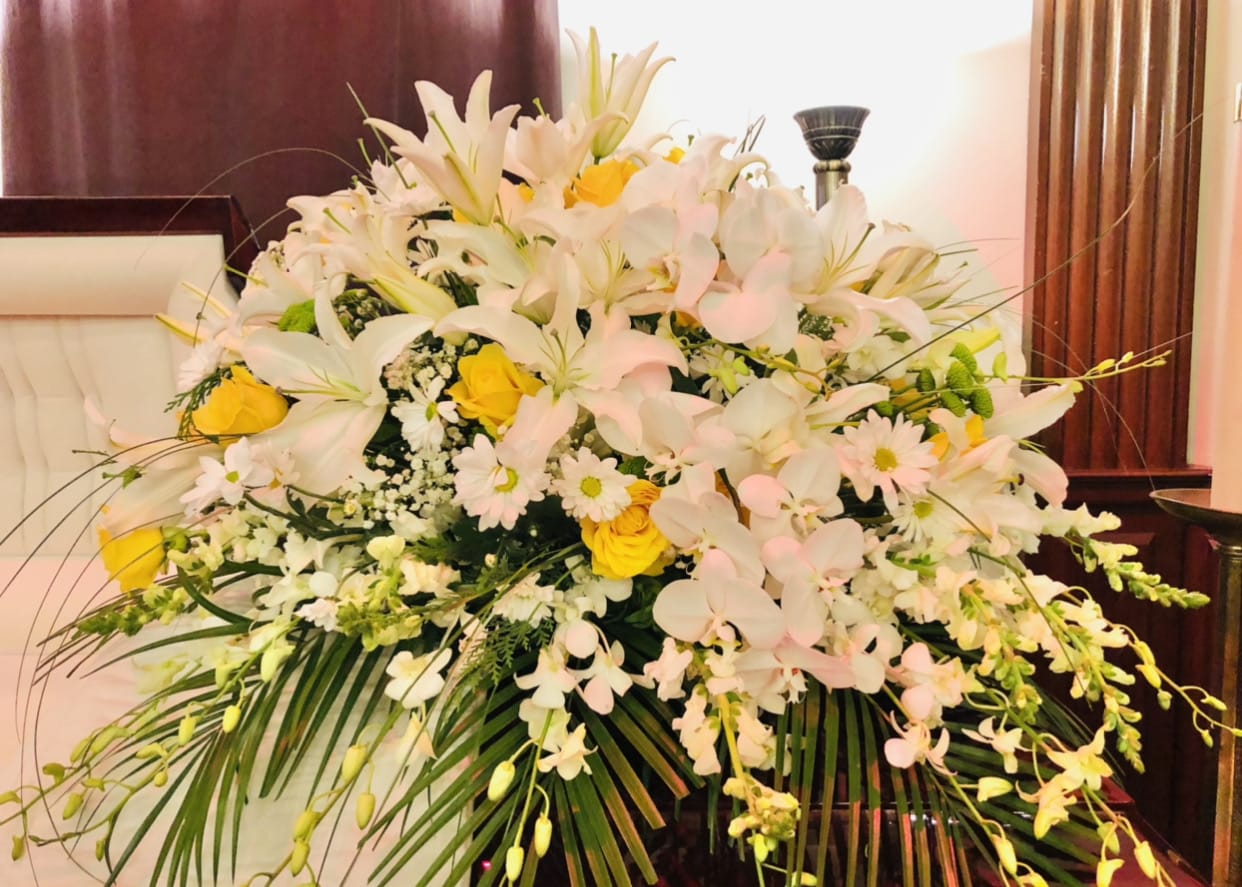 Casket 4 - Beautiful yellow and white casket arrangment featuring lilies, orchids, daises, baby breathe, and green accents.