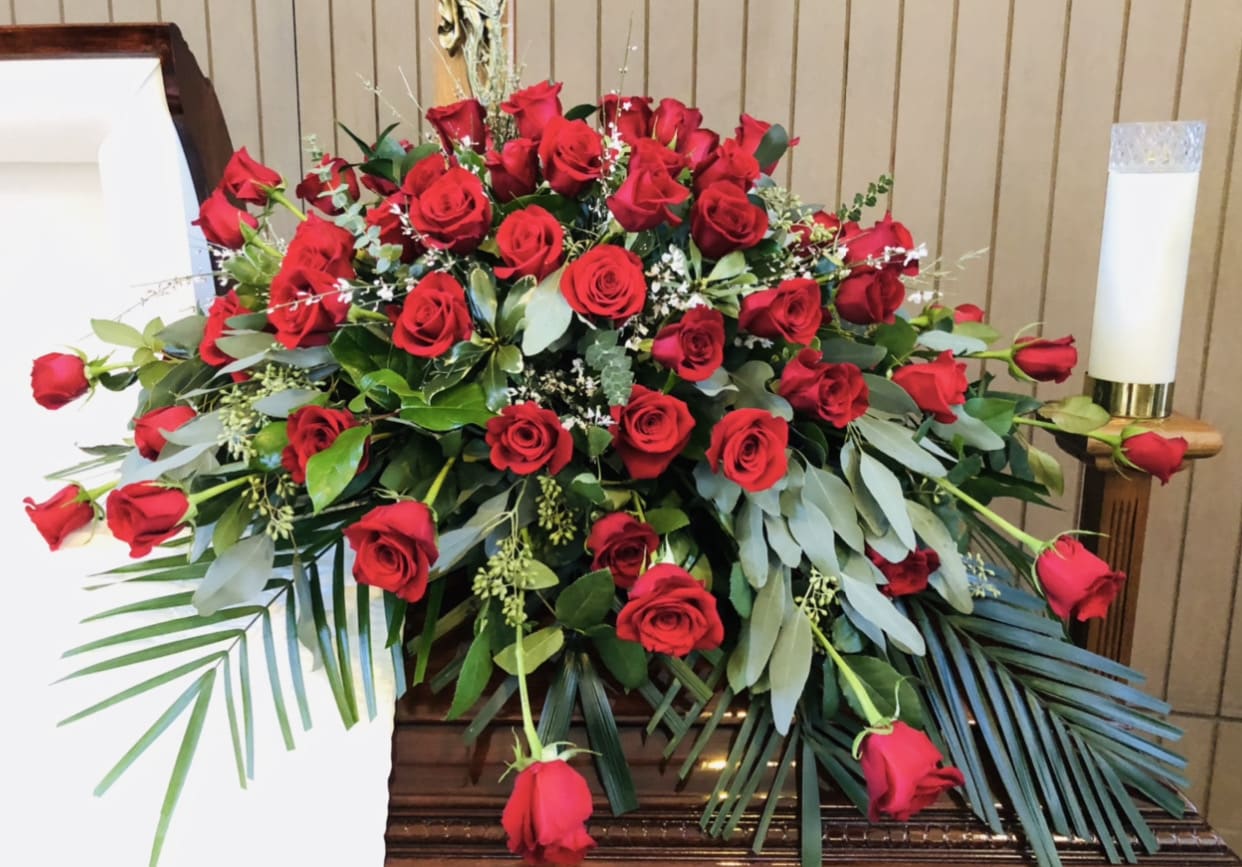 Casket 7 - Beauitful and vibrant red casket arrangement featuring roses with white and green accents.