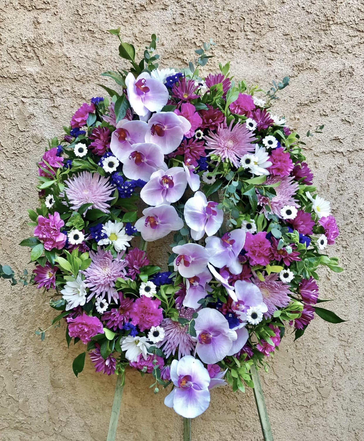 Ladder of Love - Beautiful purple and lavender standing funeral spray arrangement featuring orchids, mums, daises, with violet and green accents.
