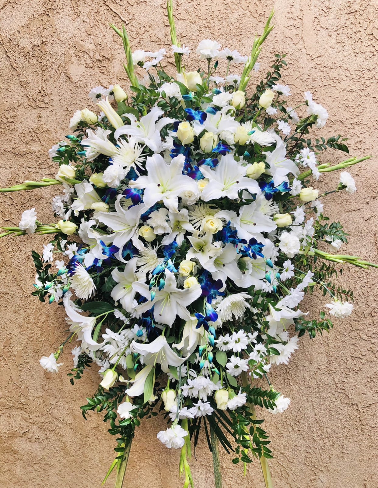 Sprouts of Light - Beautiful white and blue standing funeral spray arrangement featuring lilies, orchids, gladius, daises, roses, and green accents.