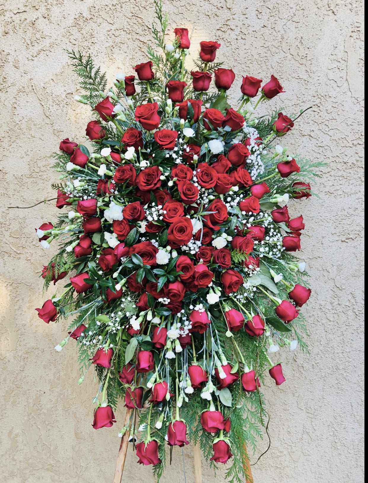 Life of Love - Beautiful red standing funeral spray arrangement featuring roses, carnations, baby breathes, and green accents.
