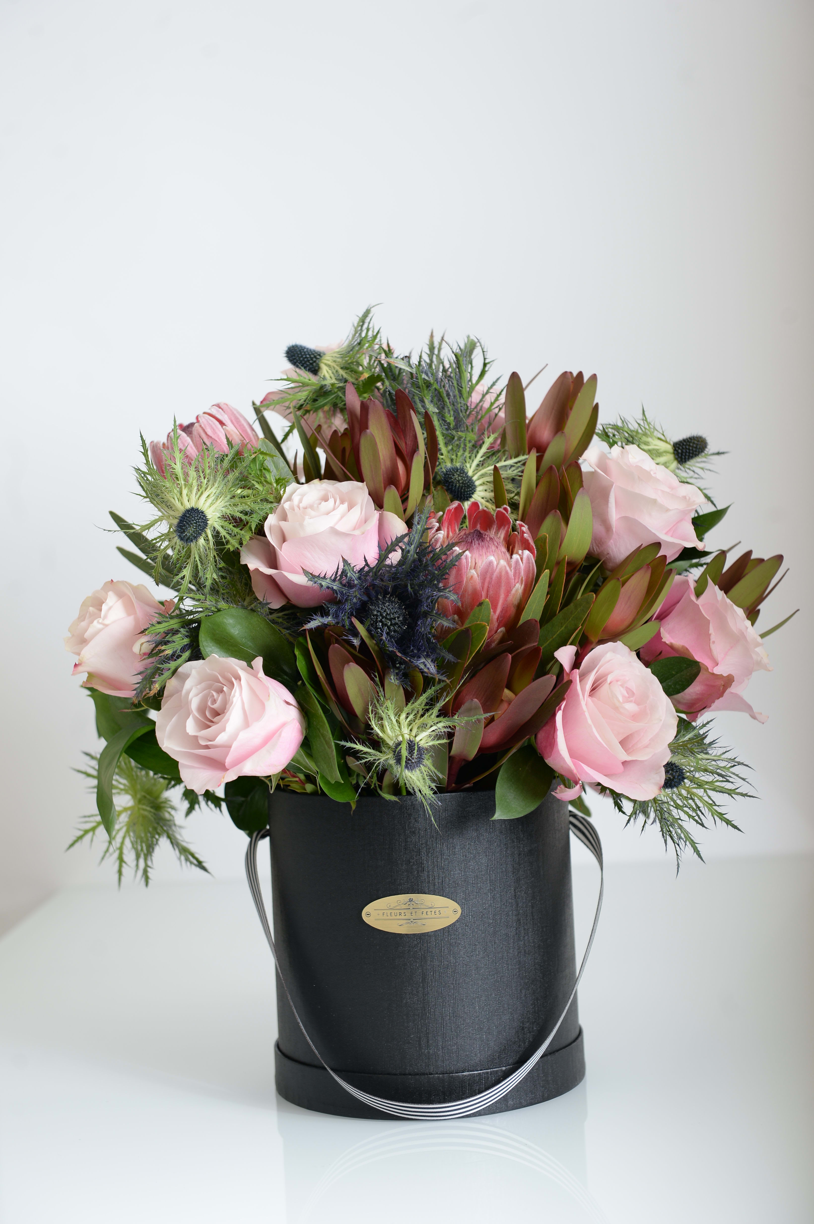 Rhodochrosite - Featuring fresh flowers. Adding Eryngium to this arrangement enhances creative thinking while soft roses bring calmness. Designed in our signature box.  *Due to Covid-19, some flowers may not be available. Fleurs et Fetes reserves the right to adjust the flowers and color depending on availability*
