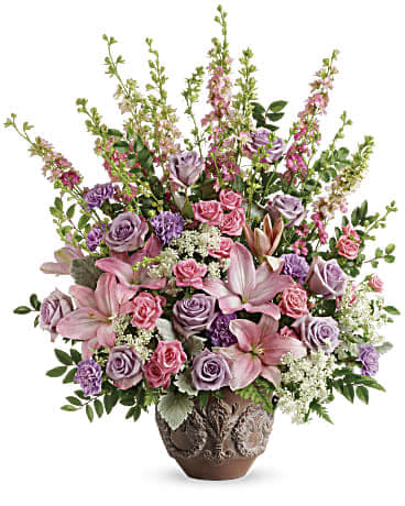 Teleflora's Soft Blush Bouquet - Like a whisper from heaven, the soft pinks and lavenders in this feminine arrangement bring peace and hope in a time of loss. Presented in a large antiqued pot, it's a loving tribute all will appreciate. This soft pink arrangement features lavender roses, pink spray roses, pink asiatic lilies, lavender carnations, pink larkspur, queen anne's lace, huckleberry, dusty miller, and leatherleaf fern. Delivered in Teleflora's Classical Garlands pot. Orientation: One-Sided