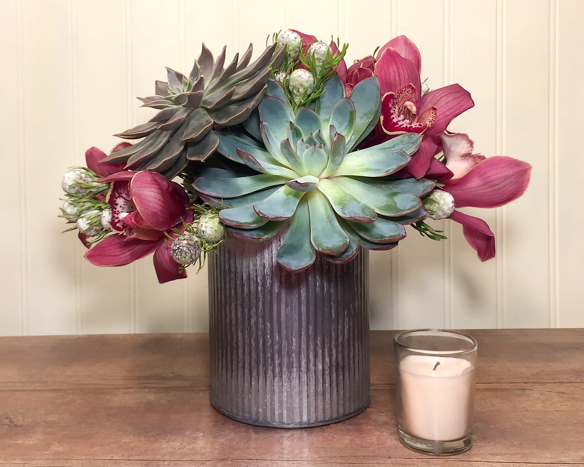 &quot;No Grit, No Pearl&quot; Succulent Arrangement - This long lasting arrangement makes a statement to your sweetie that you embrace everything that makes them unique. We've filled a rustic metal container with cut succulents, seasonal cymbidum blooms and accented it all with tiny pearl protea.  Size Approx 10&quot; x 8&quot;  *Due to availability, on occasion it may be necessary to substitute a certain flower or container for your order.