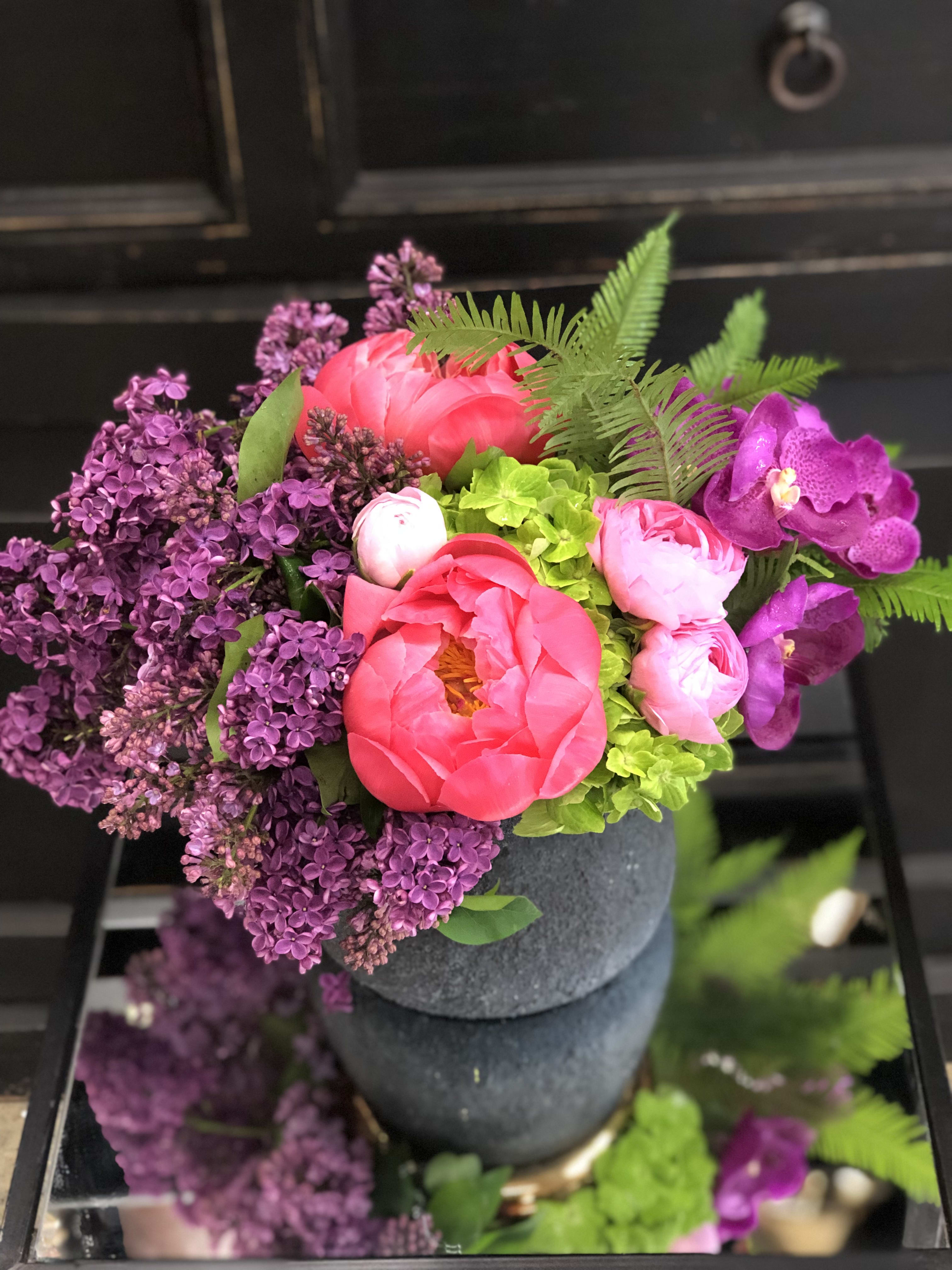 Lavish lilacs   - This is a sweet arrangement of lilacs, green hydrangeas, pink rancorous, orchids and coral charm peonies in a ceramic designer container.  Approximately 15&quot;x18&quot;. 