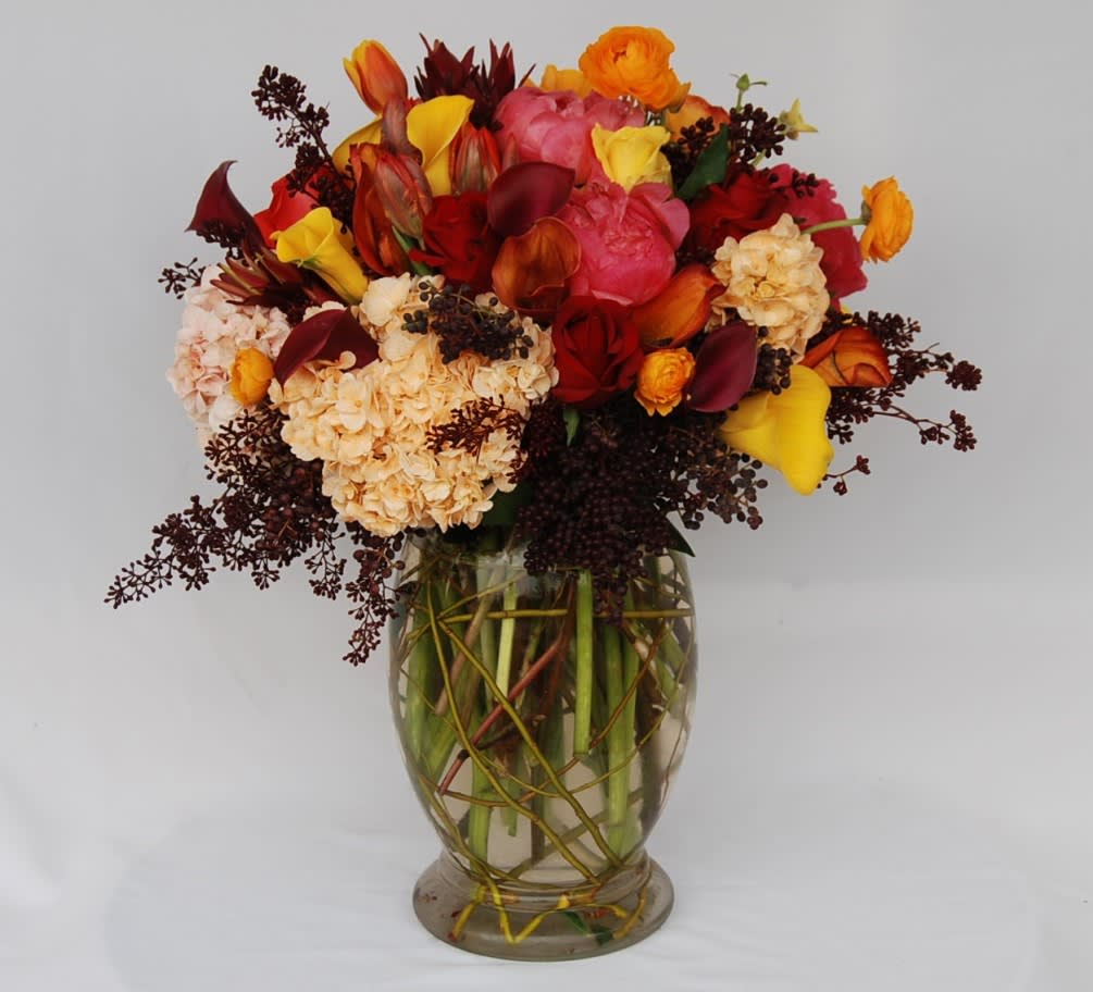 Sun Valley CA Flowers - A vase filled with hydrangeas, coral peonies, gold, orange, burgundy calla lilies, orange tulips, red roses, and orange Ranunculus, accented with seeded eucalyptus and curly willow.