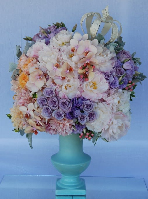 Fit For A Queen Fit For A Queen - An arrangement filled with roses, dahlias, garden roses, lisianthus, peonies, hydrangeas, phalaenopsis orchids, pink hypericum, with dusty miller in a ceramic urn.